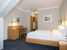 Una habitación de hotel con una cama, un escritorio, una silla y un armario.