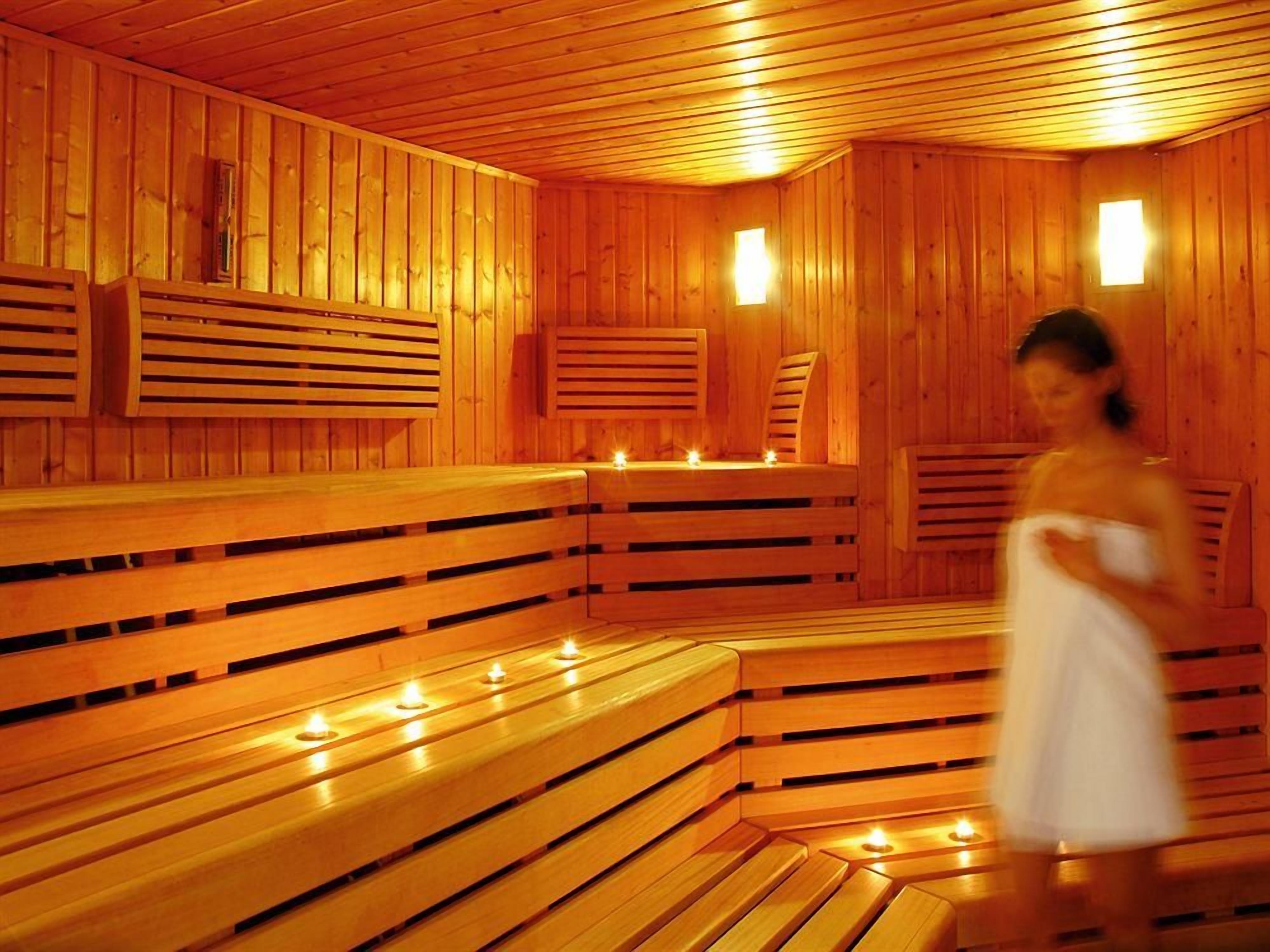Un sauna avec des bancs en bois et une personne enveloppée dans une serviette blanche.