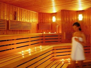 A sauna with wooden benches and benches, and a person in a white towel. - Victor S Residenz Teistungenburg (Teistungen)