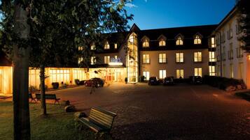 A hotel with a central courtyard, multiple windows, and a well-lit entrance.