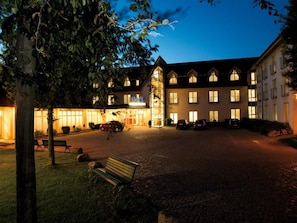 A hotel with a central courtyard, multiple windows, and a well-lit entrance. - Victor S Residenz Teistungenburg (Teistungen)