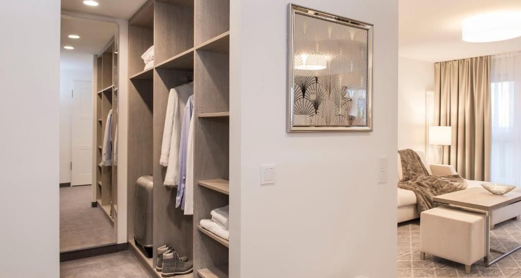 A hotel room with a walk-in closet, a framed abstract artwork, a sofa, and a coffee table.