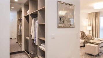 A hotel room with a walk-in closet, a framed abstract artwork, a sofa, and a coffee table.