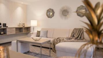 A modern living room with a sofa, coffee table, and decorative wall mirrors.