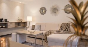 Una sala moderna con sofá, mesa de centro y espejos decorativos en la pared.