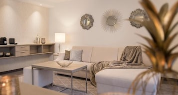 Una sala moderna con sofá, mesa de centro y espejos decorativos en la pared.