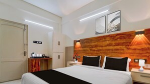 Une chambre d’hôtel comprenant un lit, des tables de chevet, une tête de lit en bois, des œuvres d’art au mur et un mini-bar.
