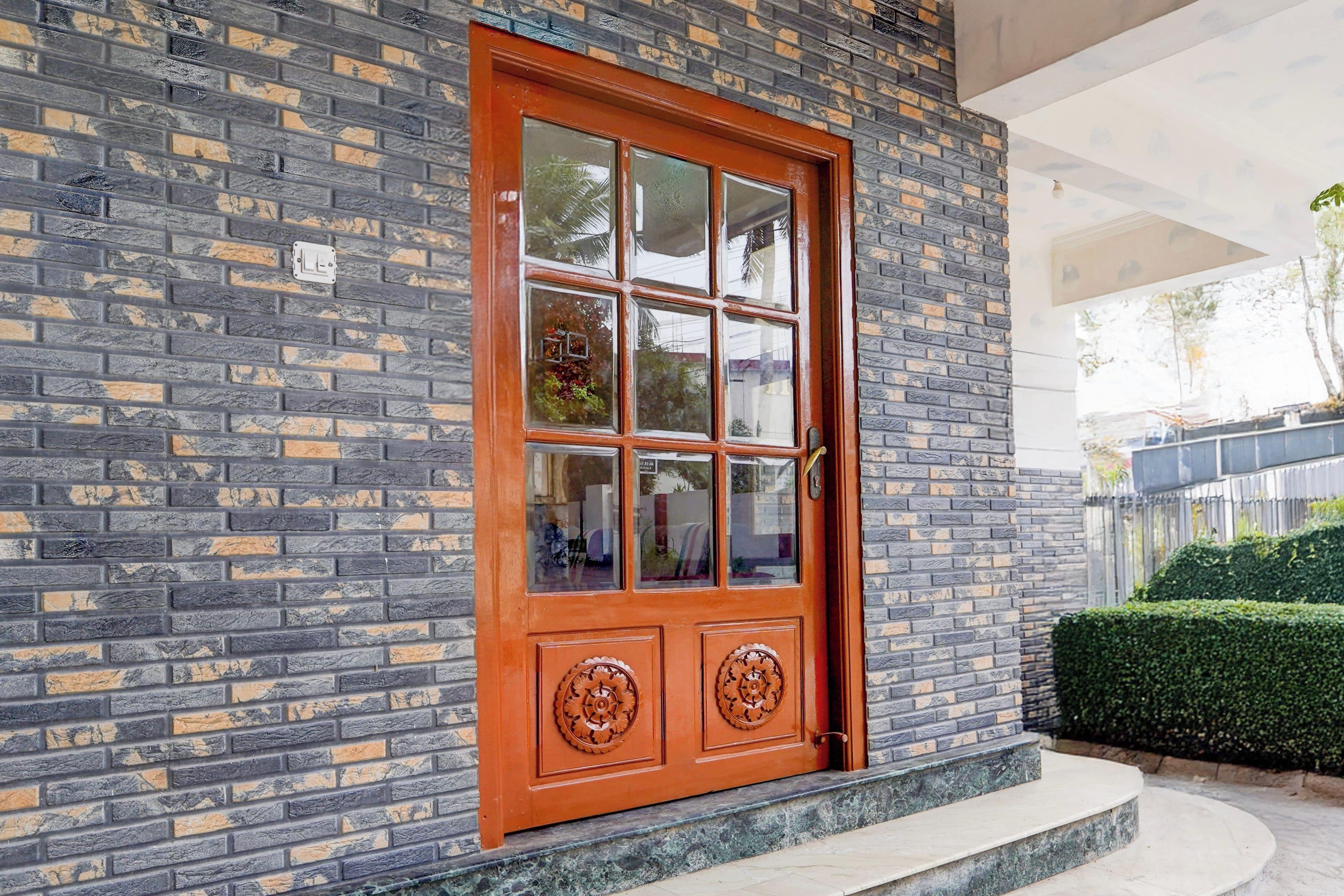 Un edificio de ladrillo con una gran puerta de madera que tiene un panel de vidrio y tiradores de metal decorativos.