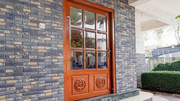 Un edificio de ladrillo con una gran puerta de madera que tiene un panel de vidrio y tiradores de metal decorativos.