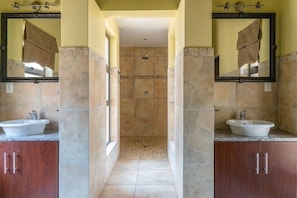 Une salle de bain avec deux lavabos, une douche et un miroir de chaque côté.