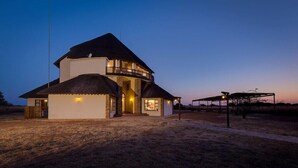 A two-story house with a balcony, a covered porch, and a well-lit entrance. - Zebula Golf Estates & Spa (Bela-Bela)