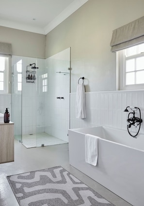 Un baño moderno con cabina de ducha de vidrio, una bañera independiente y un espejo grande.