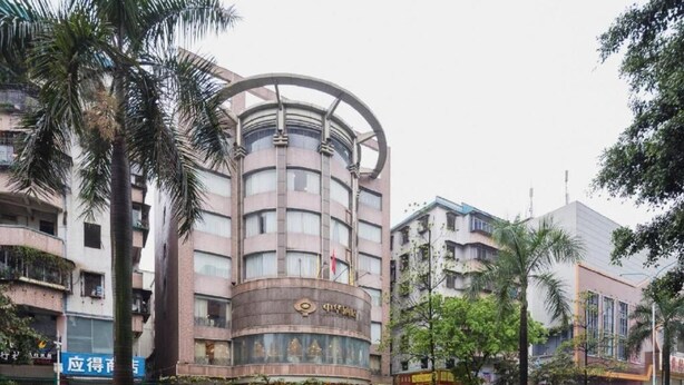 Un hôtel à plusieurs étages, doté d’une façade incurvée et entouré de palmiers et d’autres plantes.