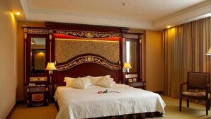 Une chambre d’hôtel avec un grand lit, deux lampes de chevet, une tête de lit en bois, une table de chevet et une chaise.