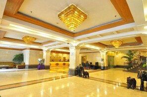 Eine geräumige Lobby mit einer Rezeption, einer Treppe und einer Kandelaber.