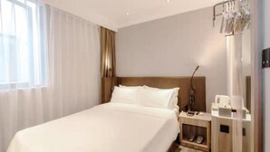 A hotel room with a large bed, a bedside table, a nightstand, a lamp, a shoe rack, and a trash bin. - Jinjiang Inn Shanghai East China Normal University (Shanghai)