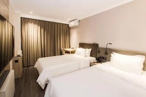 Une chambre d’hôtel avec deux lits, un bureau, une chaise, une lampe et un appareil de climatisation.