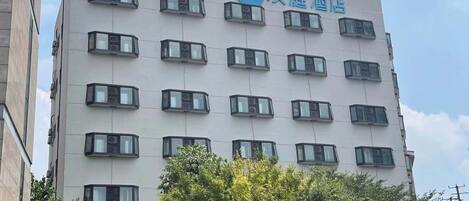 Edifício de hotel com várias andares e fachada moderna, com uma série de janelas uniformemente espaçadas e um logotipo no topo.