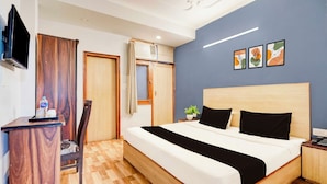 Een hotelkamer met een bed, een bureau, een stoel, een televisie en kunst aan de muur.