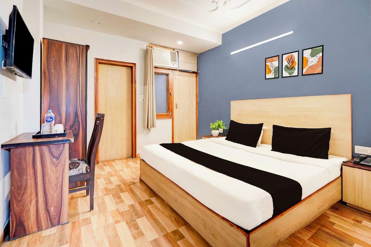 Een hotelkamer met een bed, een bureau, een stoel, een televisie en kunst aan de muur.