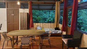A room with a round table, chairs, a bed, and large windows with curtains. - Santa Juana Lodge Nature Reserve (Naranjito)