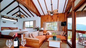 A room with a bed, a sofa, a dining table, and a balcony with a view. - Santa Juana Lodge Nature Reserve (Naranjito)