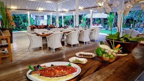 Un restaurant à thème tropical, proposant un plat de poisson copieux, un assortiment de légumes et une vue sur le jardin.
