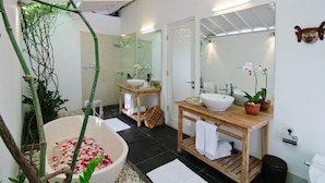 Une salle de bain moderne avec une baignoire sur pieds, deux vasques et un grand miroir.