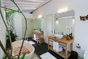 A modern bathroom with a freestanding bathtub, two sinks, and a large mirror. - Villa Sipo (Keroboken Kelod)