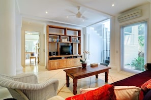 A living room with a television, bookshelf, and a coffee table. - Villa Sipo (Keroboken Kelod)