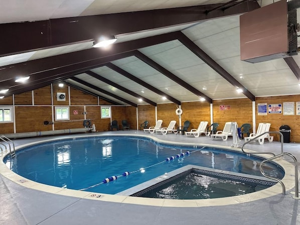 Una piscina interior amb zona de salts, envoltada de gandules i una paret de fusta.