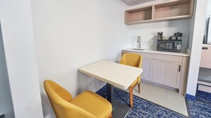 A compact kitchen with a microwave, coffee maker, and a small table with two chairs. - All Seasons Inn And Suites (Buzzards Bay)