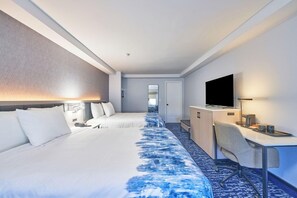 Habitació d'hotel amb dos llits, un escriptori, una televisió i un mirall.
