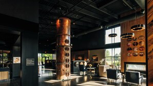 Un vestíbulo amplio con una columna cilíndrica central, zonas de estar y una pared que exhibe objetos circulares.