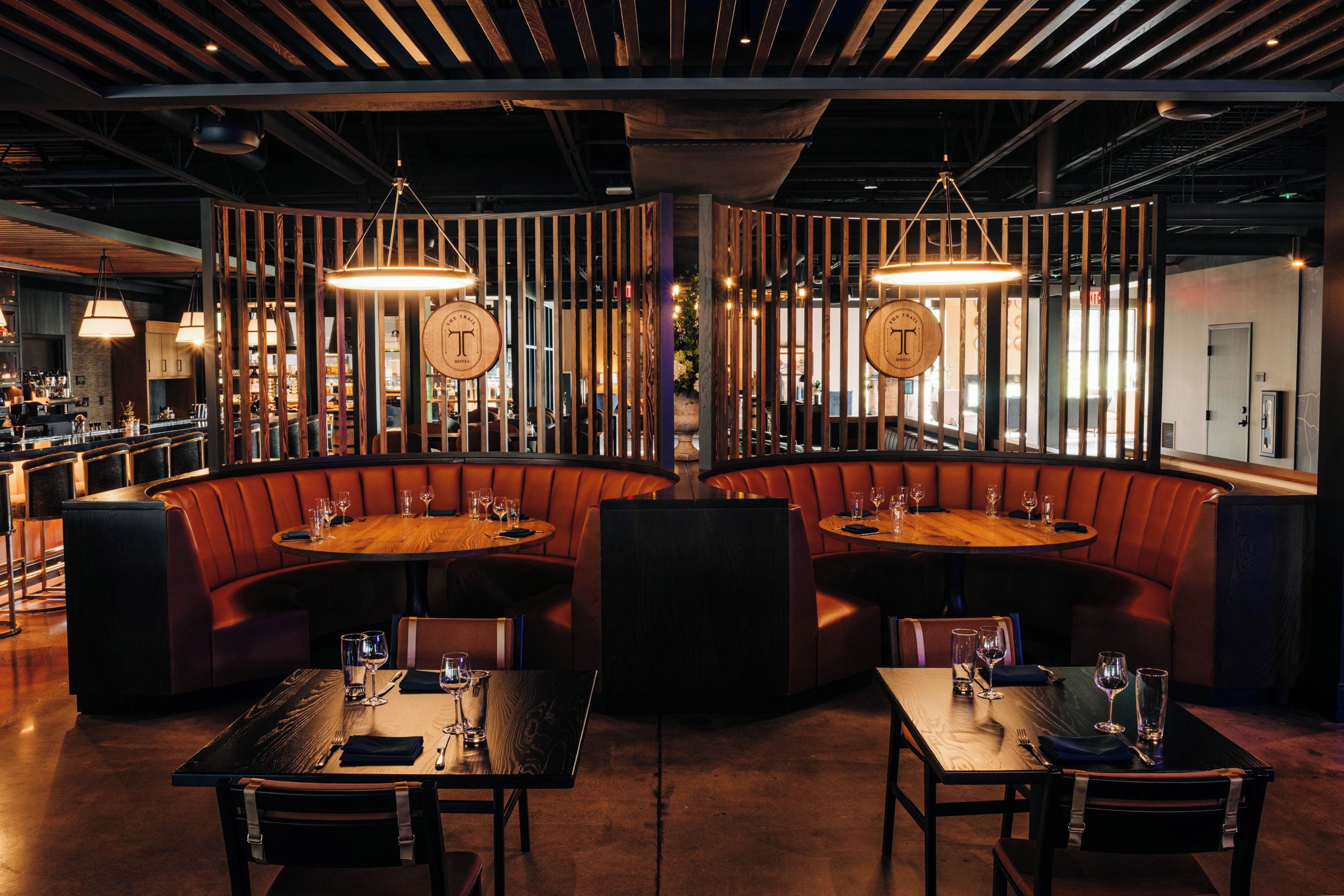 A restaurant with booths and tables, wooden accents, and pendant lighting.