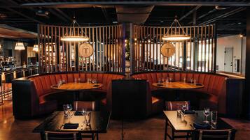 A restaurant with booths and tables, wooden accents, and pendant lighting.