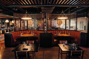 A restaurant with booths and tables, wooden accents, and pendant lighting. - Quality Inn Bardstown (Bardstown)