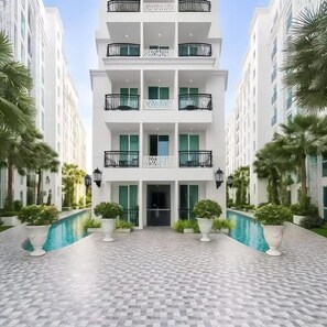 A multi-story hotel with a central courtyard, a swimming pool, and a checkered floor pattern. - Residence One Bangkok (Muang Pattaya)