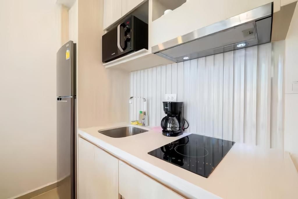 A modern kitchen with a built-in refrigerator, a coffee maker, and a black induction cooktop.
