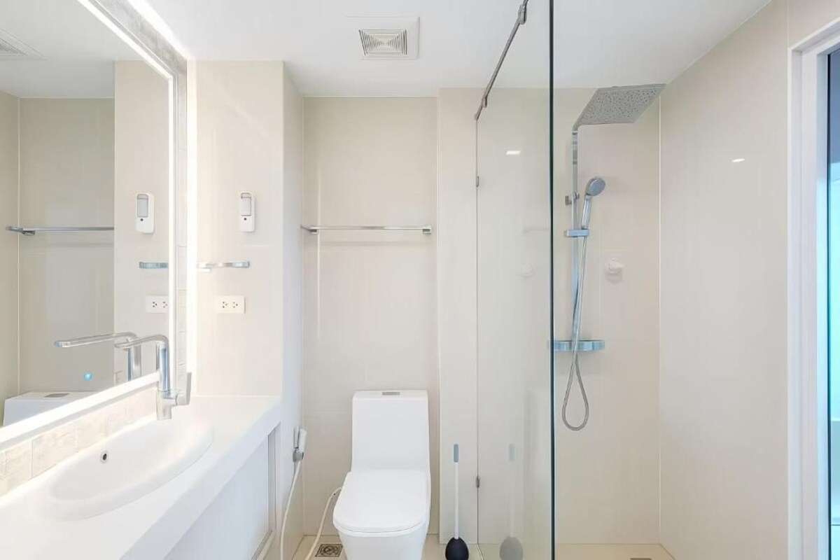 A modern bathroom with a white sink, toilet, and glass-enclosed shower.