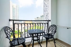 A balcony with a metal railing, two chairs, and a small table. - Residence One Bangkok (Muang Pattaya)
