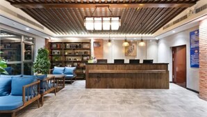 A reception area with a wooden reception desk, blue seating, and a tiled floor. - Time Walk Nostalgic Theme Hotel Beijing Prince Gongfu (Beijing)