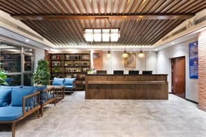 A reception area with a wooden reception desk, blue seating, and a tiled floor. - Time Walk Nostalgic Theme Hotel Beijing Prince Gongfu (Beijing)