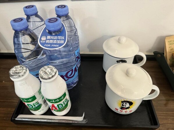 Ein Tablett mit Wasserflaschen, zwei weißen Tassen und einem Löffel.