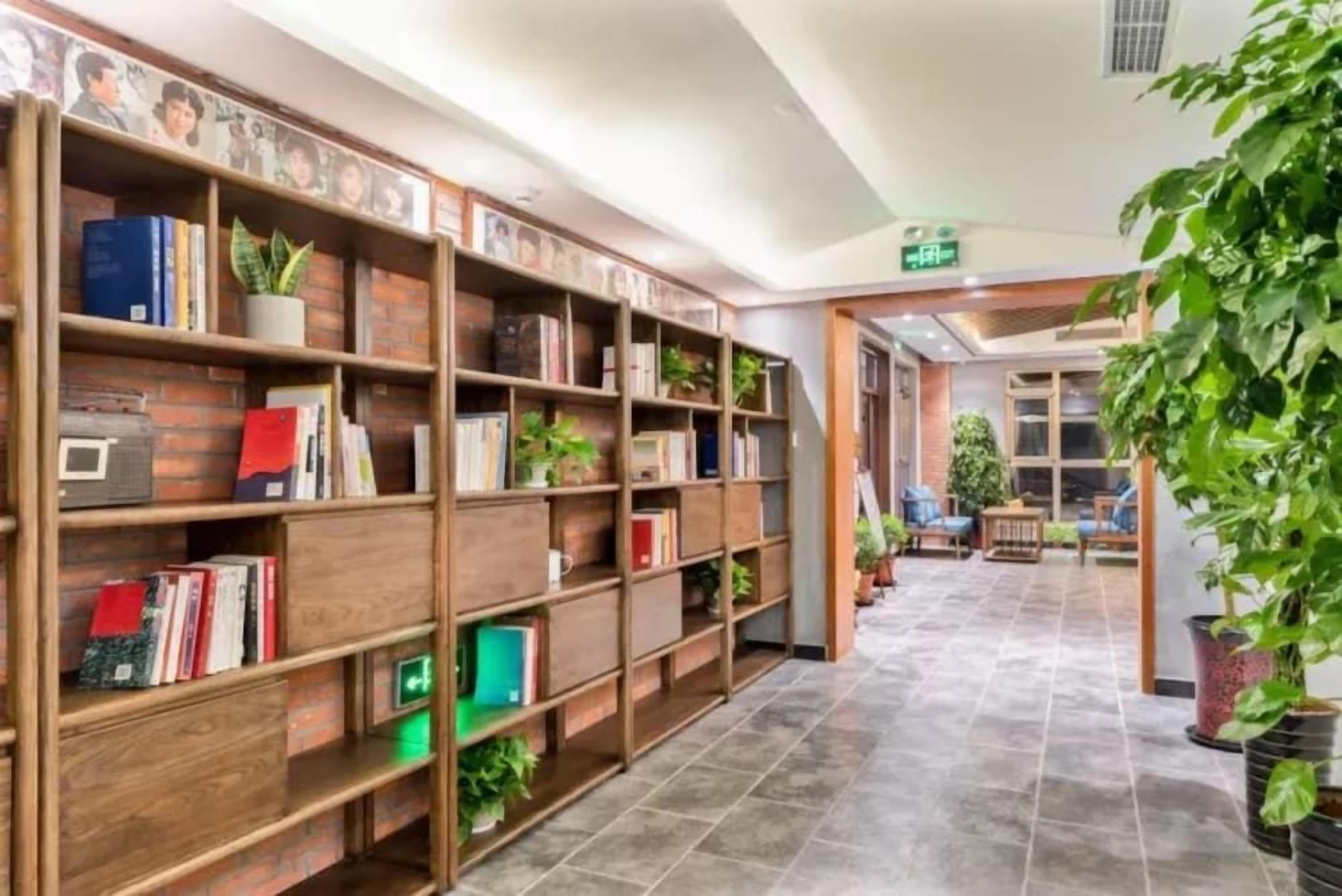 A library with bookshelves, a tiled floor, and potted plants.