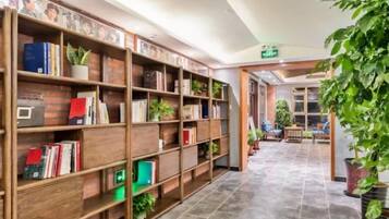 A library with bookshelves, a tiled floor, and potted plants.