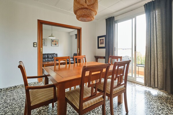 A dining area with a wooden table and chairs, a mirror, and a view of the outdoors through a large window. - Puerto Atarazanas Flat – Apartment in Valencia next to the Atarazanas (València)
