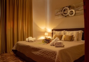 A hotel room with a bed, pillows, a lamp, and towels. - Kensho Skiathos Apartments (Skiathos)