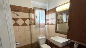 Un baño con ducha, inodoro, lavamanos y lavadora.