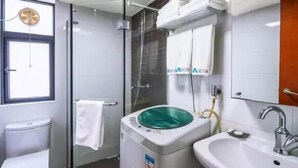 Un baño con inodoro, ducha con mampara de vidrio, lavabo y espejo.